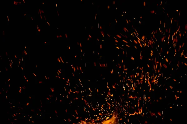 Siyah arkaplanda kıvılcımlar saçan bir ateş alevi