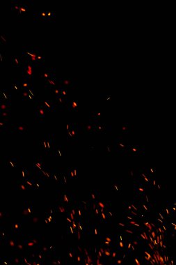 Siyah arkaplanda kıvılcımlar saçan bir ateş alevi