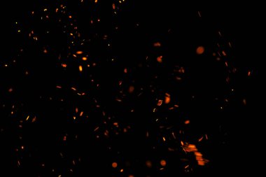 Siyah arkaplanda kıvılcımlar saçan bir ateş alevi