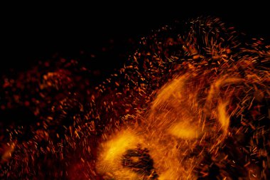 Siyah arkaplanda kıvılcımlar saçan bir ateş alevi