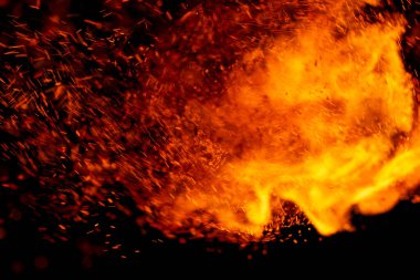 Siyah arkaplanda kıvılcımlar saçan bir ateş alevi