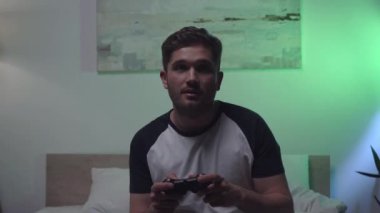 KYIV, UKRAINE - 15 Nisan 2021: yatak odasında joystick ile oynayan adam odaklı