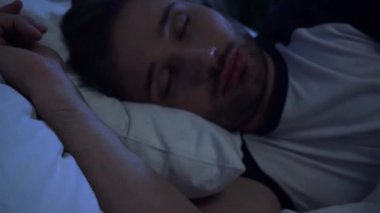 Genç adam geceleri evde uyuyor.