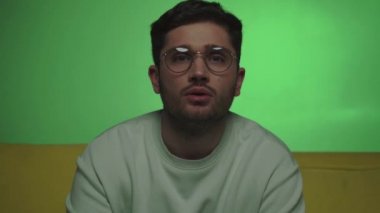 Yeşil TV izlerken TV kanallarına tıklayan hoşnutsuz bir adam