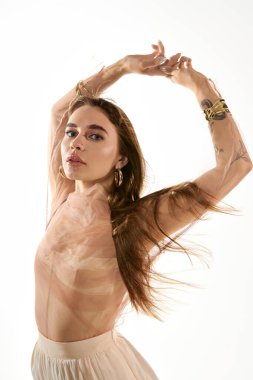 Genç bir kadın zarif ve dalgalı saçlarıyla, yumuşak bir arka planda büyülenir..