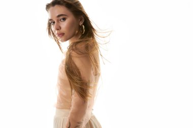 Güzel genç bir kadın zarif bir şekilde ayakta duruyor, uzun saçları zarif bir şekilde süzülüyor ve kendine güveniyor..