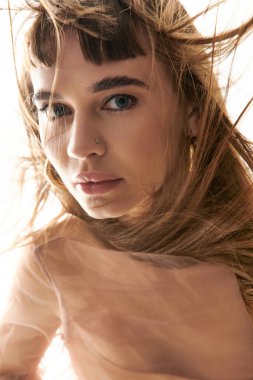 Genç bir kadın zarif pozlar verir, saçları dalgalanır kendine güven ve tarz saçar..