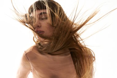 Güzel, genç bir kadın saçları hareket halindeyken poz verir. Zarafet ve kendine güvenini gösterir..