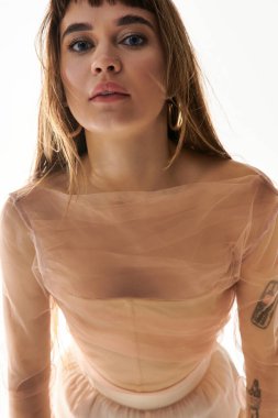 Şık bir genç kadın, hareketli bir arka plana karşı duruşuyla dikkatleri üzerine çekiyor..