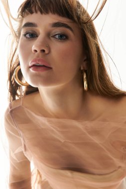 Güzel hatları olan genç bir kadın kendine güvenerek poz verir, saçları havada zarifçe süzülür..