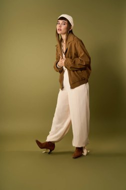 Genç bir kadın moda anlayışını gösteriyor, şık kıyafetini sanatsal bir ortamda sergiliyor..