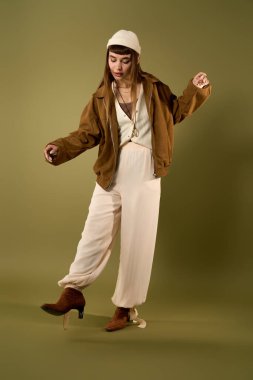 Genç bir kadın, yeşil bir zemine karşı kendine güvenen pozlarla yeni tarzını sergiliyor..