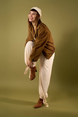 Neşeli genç bir kadın yumuşak yeşil bir arka planda neşeli bir şekilde poz verir..