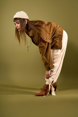 Güzel genç bir kadın, şık kıyafetini, sağlam bir arka planda poz verirken ayarlar..