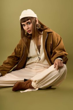 Şık genç bayan zarif bir şekilde yerde oturuyor ve modaya uygun kıyafetine güveniyor..