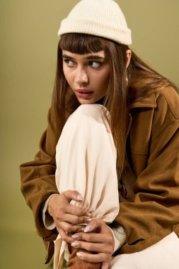 Uzun saçlı ve bereli güzel bir kadın zarif bir poz veriyor, modern moda eğilimleri sergiliyor..