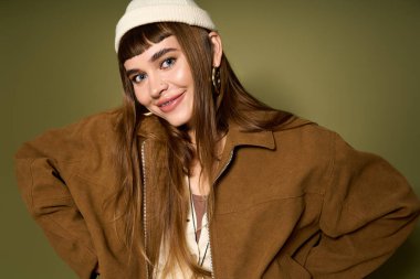 Genç ve güzel bir kadın mutlu bir şekilde poz verir, zarif tarzını bir gülümsemeyle gösterir..