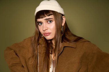 Cesur bir ifadeyle genç ve güzel bir kadın şık bir şapka ve şık bir ceket giyiyor, kendinden çok emin..