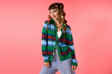 Genç bir kadın, kendine has tarzını parlak pembe bir arka plana karşı neşeli pozlarla sergiliyor..