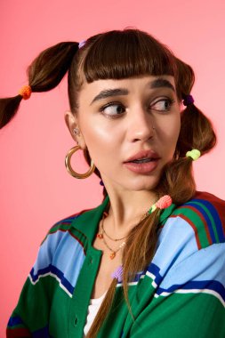 Parlak giyimli genç kadın, kendine has stilini komik örgülü saçlarıyla ve renkli aksesuarlarıyla sergiliyor..