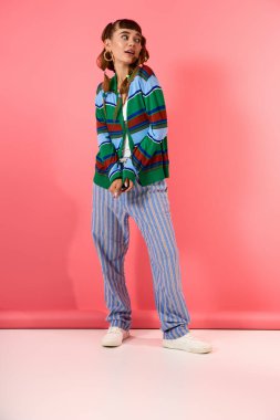 Genç ve güzel bir kadın kendine güveni tam bir şekilde duruyor, moda anlayışını sergiliyor..