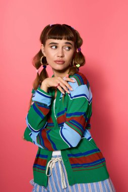 Parlak giyimli genç bir kadın neşeli bir şekilde poz veriyor, şık kıyafetini neşeli bir ortamda vurguluyor..