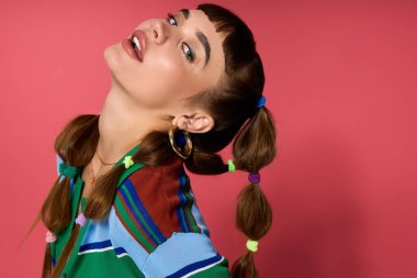 Tarz sahibi genç bir kadın renkli örgülü saçlarıyla poz veriyor, benzersiz moda tarzını sergiliyor..