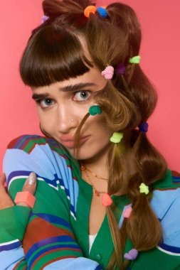 Güzel genç bir kadın kendine güvenerek poz veriyor. Eşsiz bir saç stili ve şık bir kıyafeti var. Neşe saçıyor..