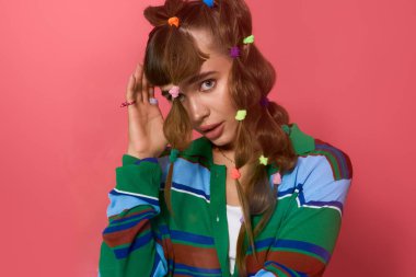 Genç bir kadın neşeli saçlarını ve neşeli gülümsemesini stüdyoda sergiliyor..