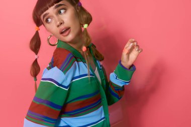 Çekici genç bayan parlak pembe bir arka plana karşı renkli saç aksesuarlarıyla poz veriyor..