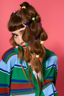 Şık bir genç kadın neşeli ve yaratıcı bir ortamda renkli saç aksesuarları sergiliyor..