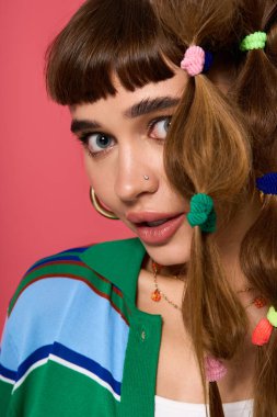 Güzel bir kadın şık poz veriyor. Renkli saçlarını ve kıyafetlerini cesur bir arka plana vuruyor..