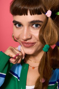 Gülümseyen genç bir kadın moda saç aksesuarlarını renkli bir kıyafetle modelliyor..