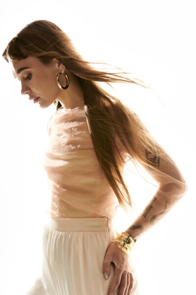 Красивая женщина стоит изящно, как мягкий свет подчеркивает ее стильный наряд и текущие волосы.