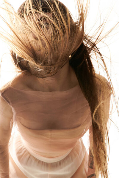 Молодая женщина с выпрямленными волосами демонстрирует свой стильный наряд, излучая красоту и уверенность.