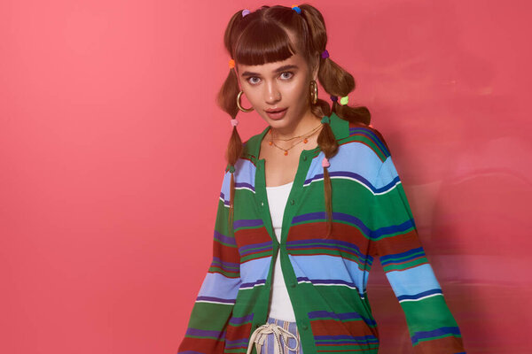 Молодая женщина с косичками и полосатым свитером излучает радость в яркой обстановке.