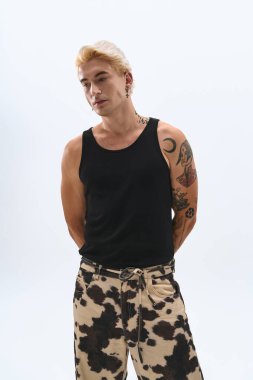 Yakışıklı bir genç adam kendine güvenerek poz veriyor, şık elbisesini ve benzersiz tarzını vurguluyor..