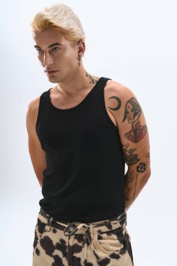 Yakışıklı genç bir adam moda anlayışını gösterip stil sahibi bir duruş sergiliyor, dövmelerini parlaklaştırıyor..