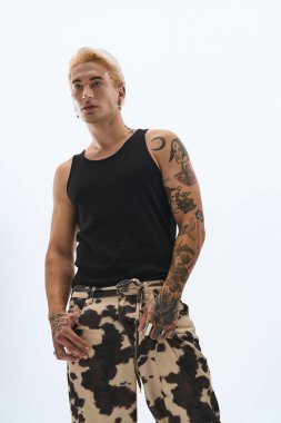 Yakışıklı genç bir adam kendine güvenerek, modern bir ortamda eşsiz moda anlayışını sergiliyor..