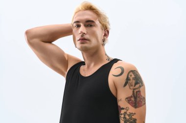 Dövmeleri olan genç adam hiç zorlanmadan poz veriyor, modaya uygun tarzını ve çekiciliğini sergiliyor..