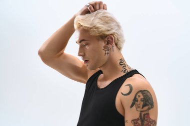 Yakışıklı genç adam kendine güvenerek poz veriyor. Eşsiz stilini ve sanatsal dövmelerini içeride gösteriyor..