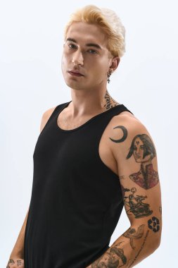 Yakışıklı genç adam gösterişli, şık bir elbise içinde basit bir arkaplana karşı güvenle poz veriyor..