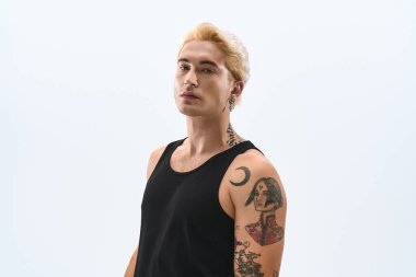 Moda dövmeleri olan genç bir adam kendine güvenerek şık görünüşünü sergiliyor..