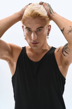 Şık bir genç adam, temiz bir arkaplanda kendine güvenerek poz verir..