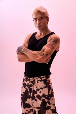 Genç bir adam moda anlayışını şık bir kıyafet ve dövmeyle sergiliyor..