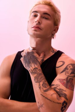 Genç adam kendine güvenerek poz veriyor. Dövmeleri sergileniyor. Benzersiz tarzını ve cazibesini sergiliyor..