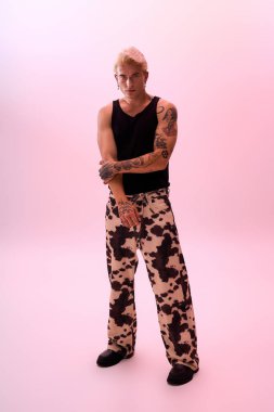 Genç bir adam kendine güvenerek renkli bir atmosferle çevrili şık bir kıyafetin içinde poz veriyor..