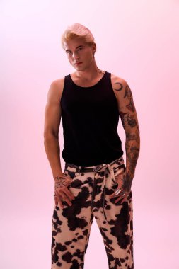 Yakışıklı genç adam kendine güvenerek modaya uygun bir şekilde poz veriyor, eşsiz stilini ve yeteneğini vurguluyor..