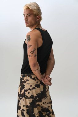 Yakışıklı genç adam modaya uygun bir şekilde poz veriyor. Benzersiz stilini ve dövmelerini vurguluyor..