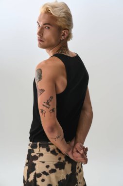 Yakışıklı genç adam çağdaş bir stüdyo arka planında şık bir pozla güven yayıyor..